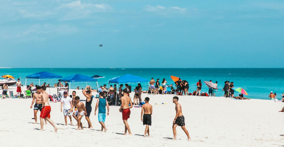 Crowds enjoy a sunny summer day at Miami Beach with clear blue skies and white sand