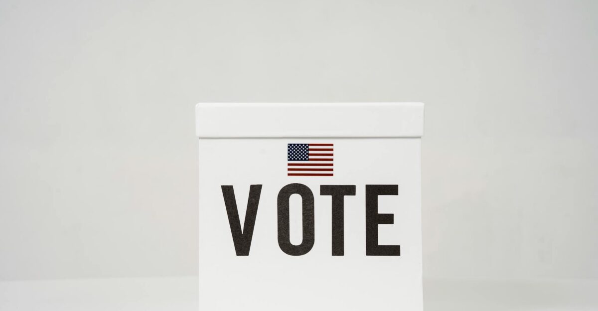A minimalist ballot box with Vote and an American flag symbolizing elections