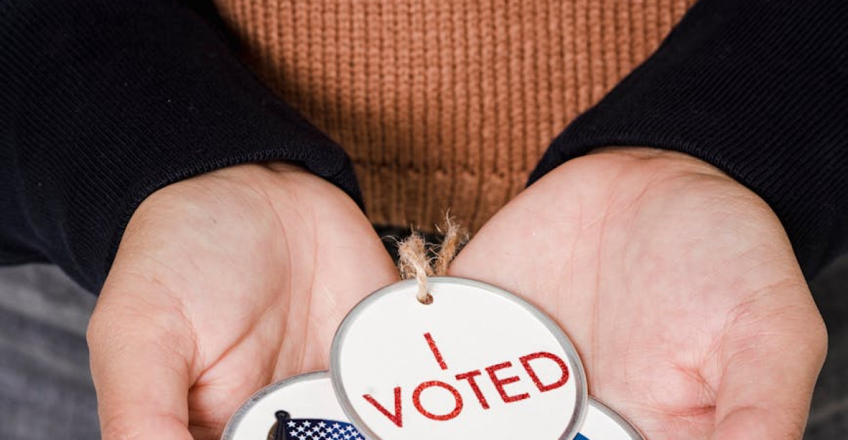 Close-up of hands holding I Voted badges with USA flag symbolizing democratic participation