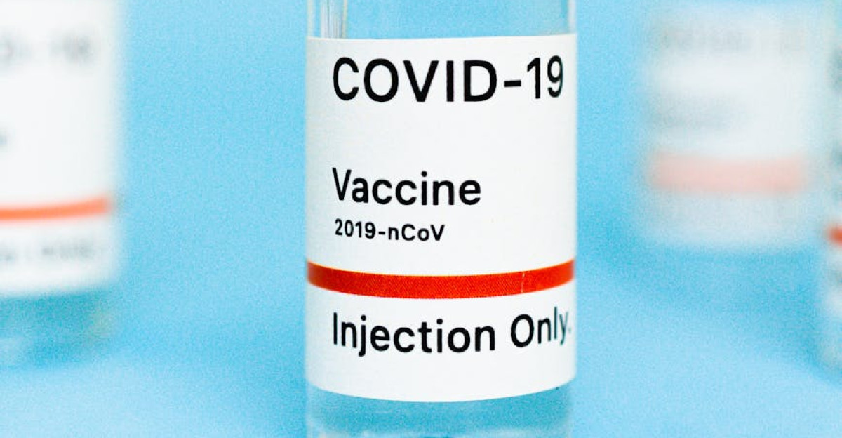 Macro shot of a COVID-19 vaccine vial labeled Injection Only on a blue backdrop