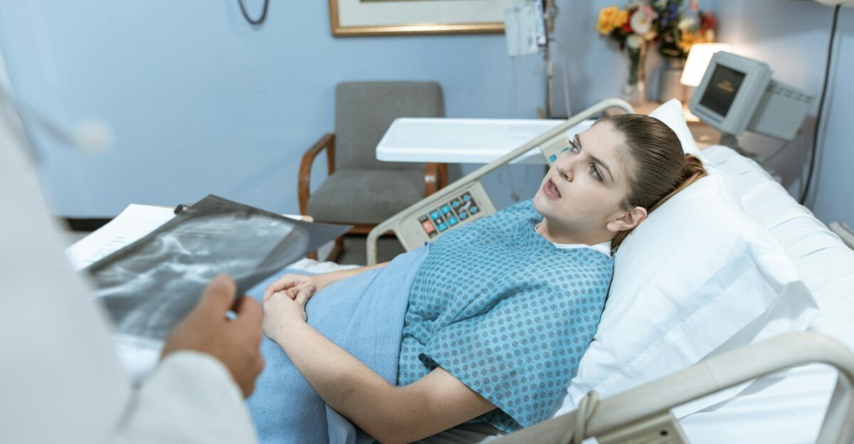 Caucasian woman in hospital bed receiving care from healthcare professional