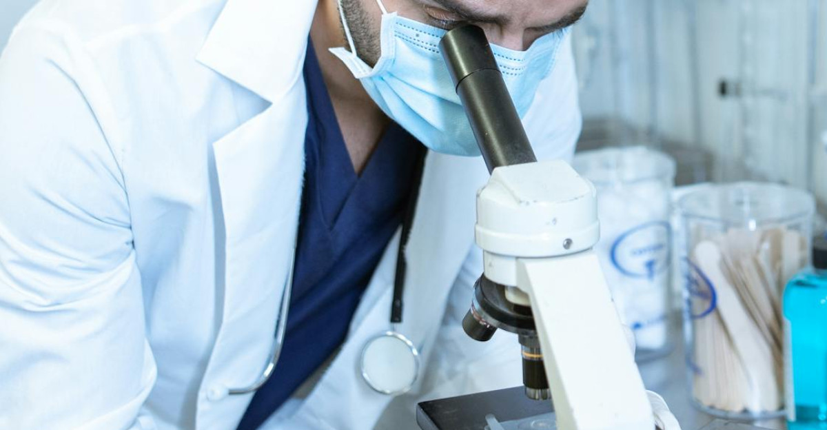 Scientist in a lab coat examining samples using a microscope
