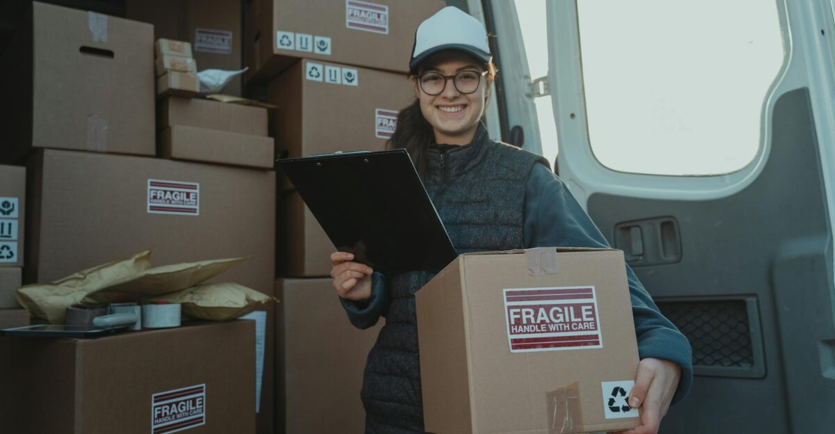 A cheerful delivery woman prepares parcels inside a van ensuring careful handling
