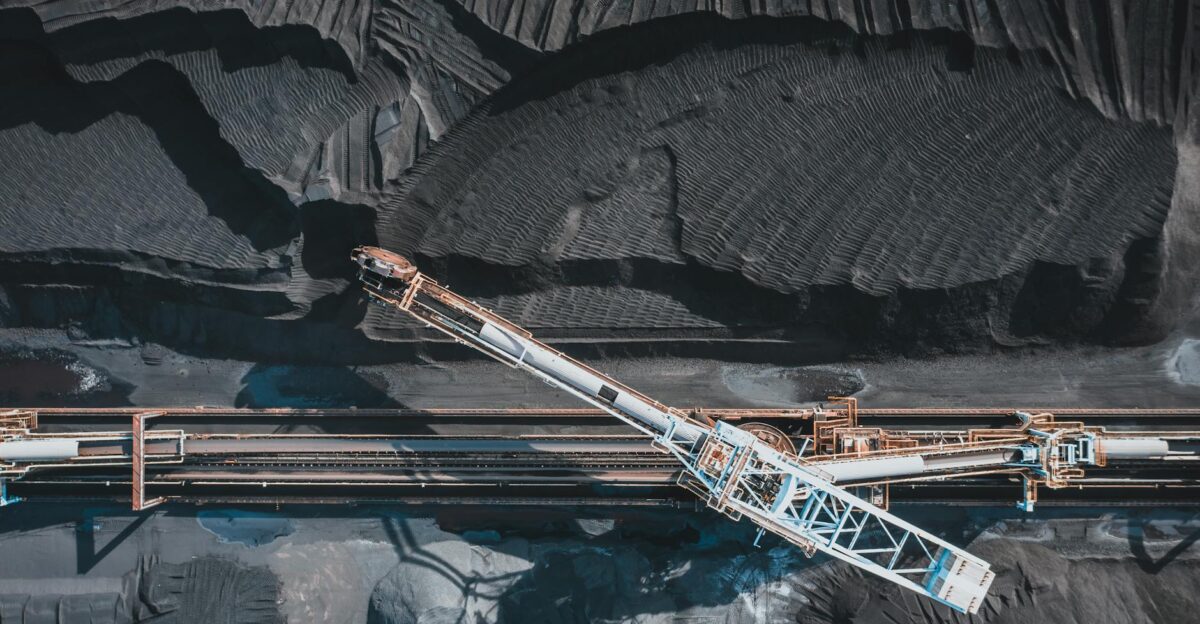 Top view of modern industrial machinery working with black natural coal in daylight