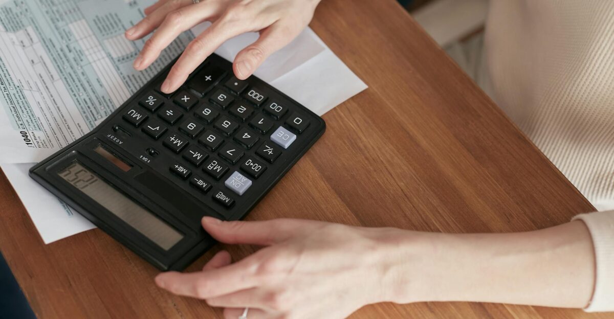 Close-up of a woman using a calculator and reviewing bills at home