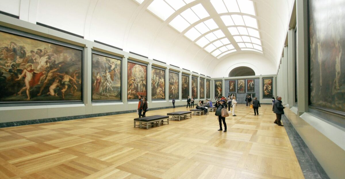A wide view of a museum hall showcasing famous paintings and visitors exploring the art