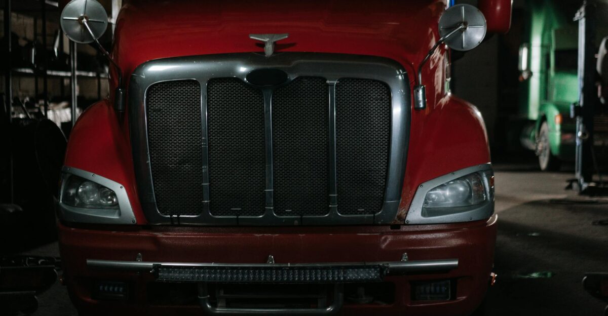 Close-up of a classic red semi truck in a dimly lit garage with chrome details
