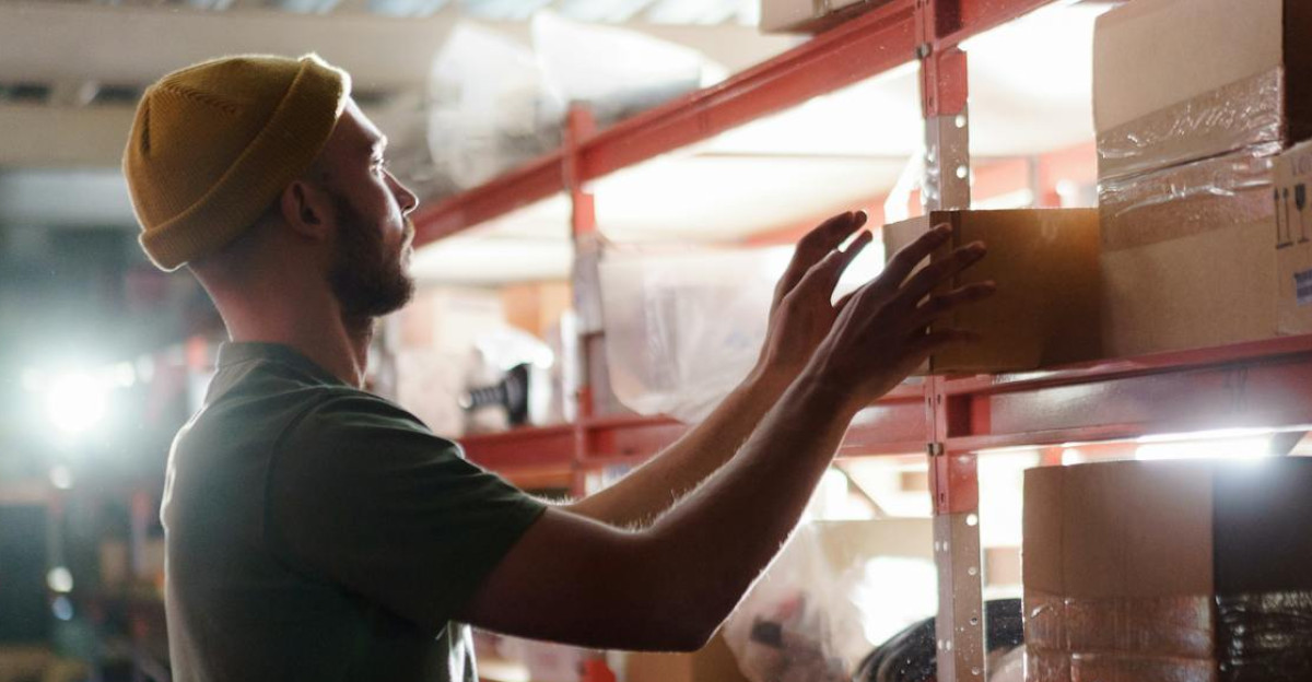 Worker organizing boxes on shelves in a warehouse focused on logistics and storage management