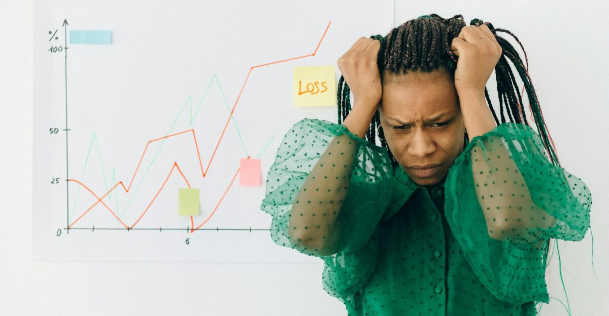 Frustrated businesswoman in green blouse analyzing a graph showing financial loss
