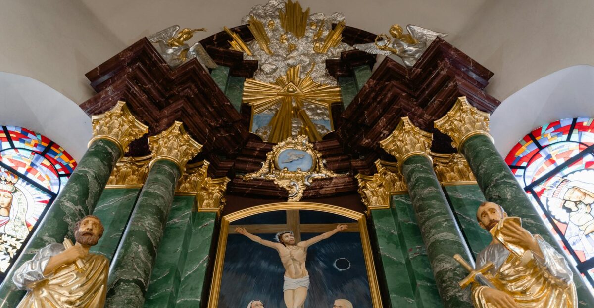 A detailed view of a church altar featuring religious statues stained glass and gold decorations