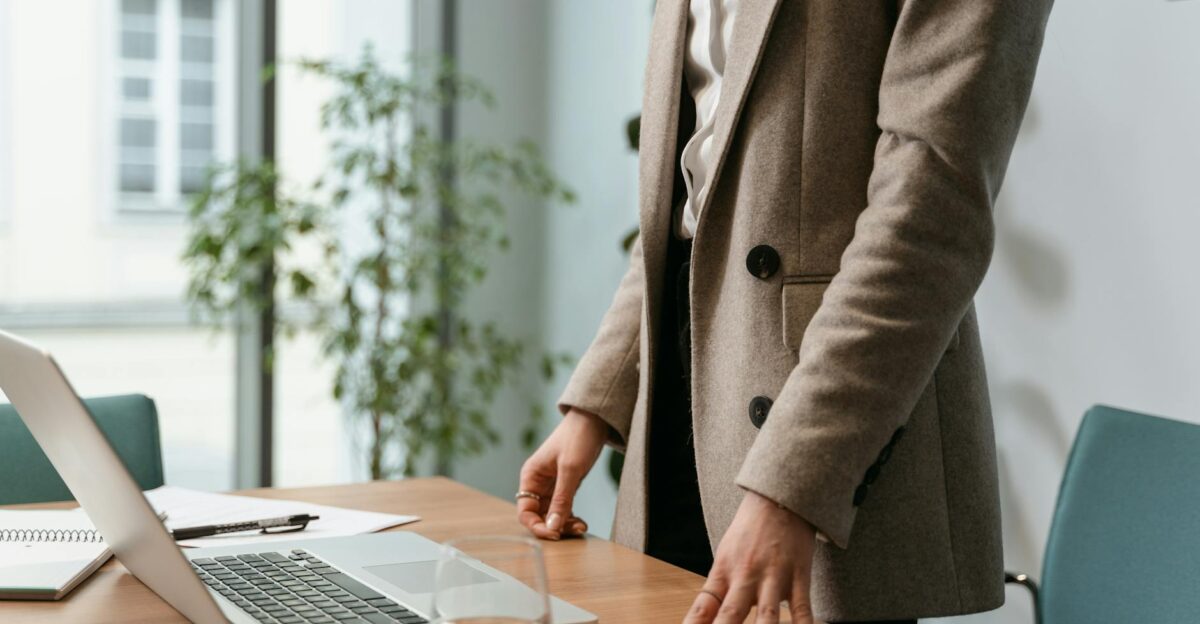 A professional businesswoman in a stylish office environment with a laptop and notes
