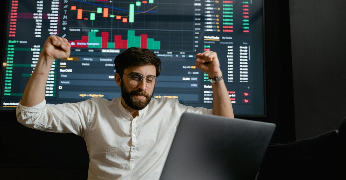 Successful businessman exults in front of a stock market display
