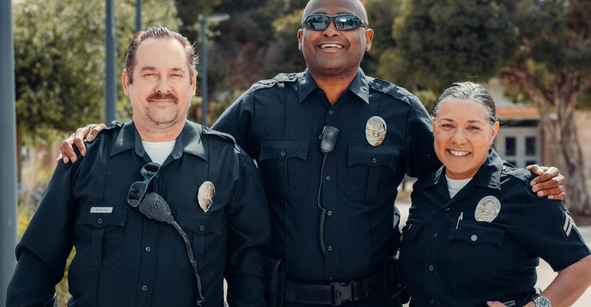 Three police officers in uniform smiling together outdoors symbolizing community and law enforcement