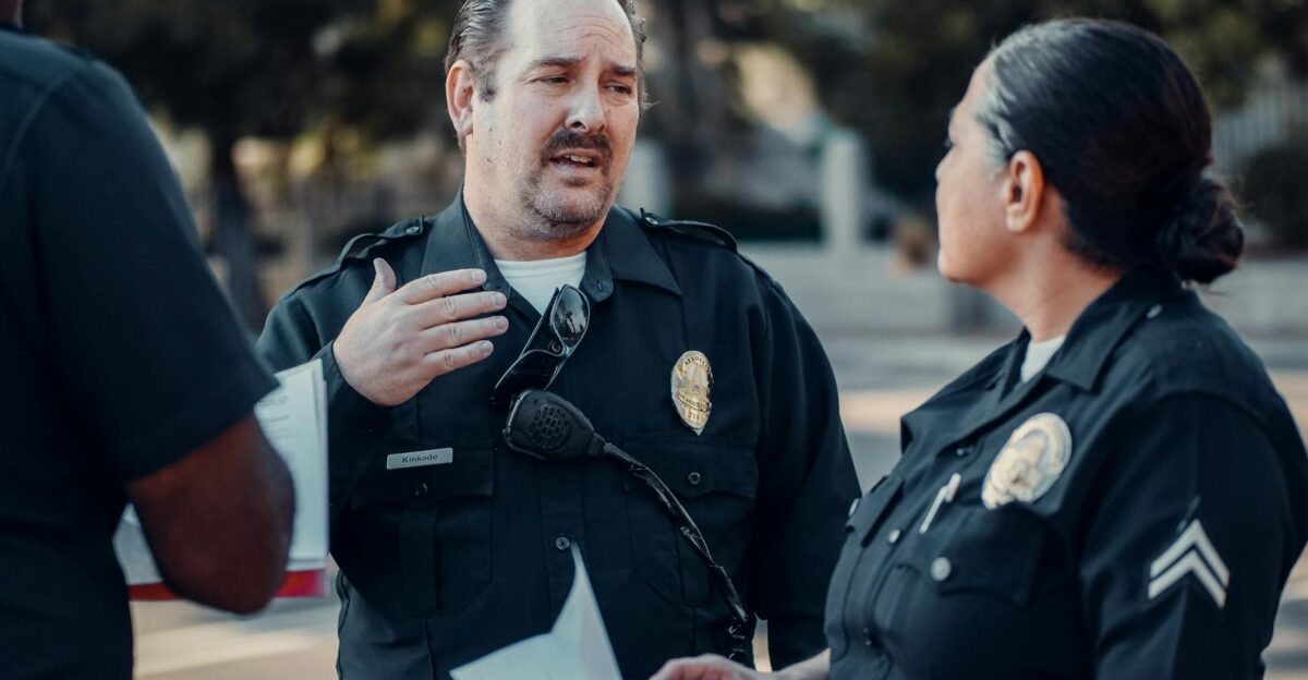 Three police officers engage in conversation outdoors showcasing teamwork