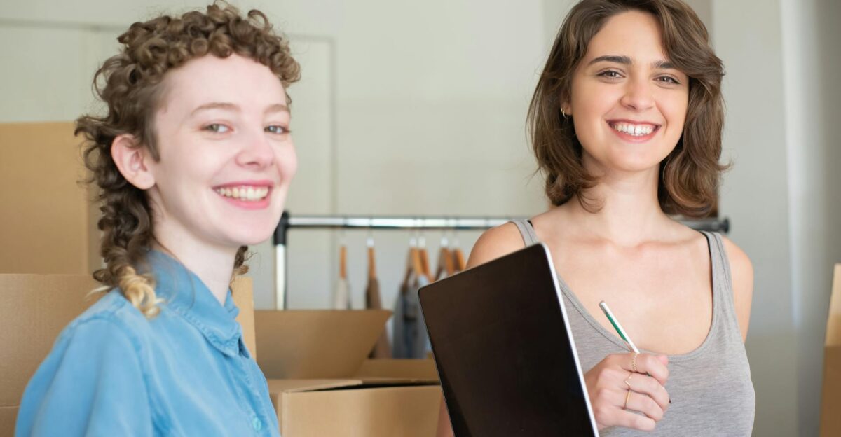 Two smiling women working together in a home-based business with boxes and a laptop