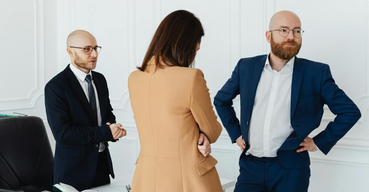 A professional trio engaged in a serious discussion inside a modern office