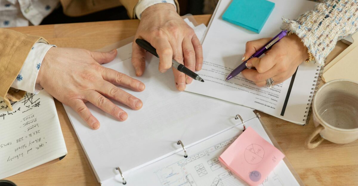 Close-up of two coworkers collaborating over documents and planning in an office setting