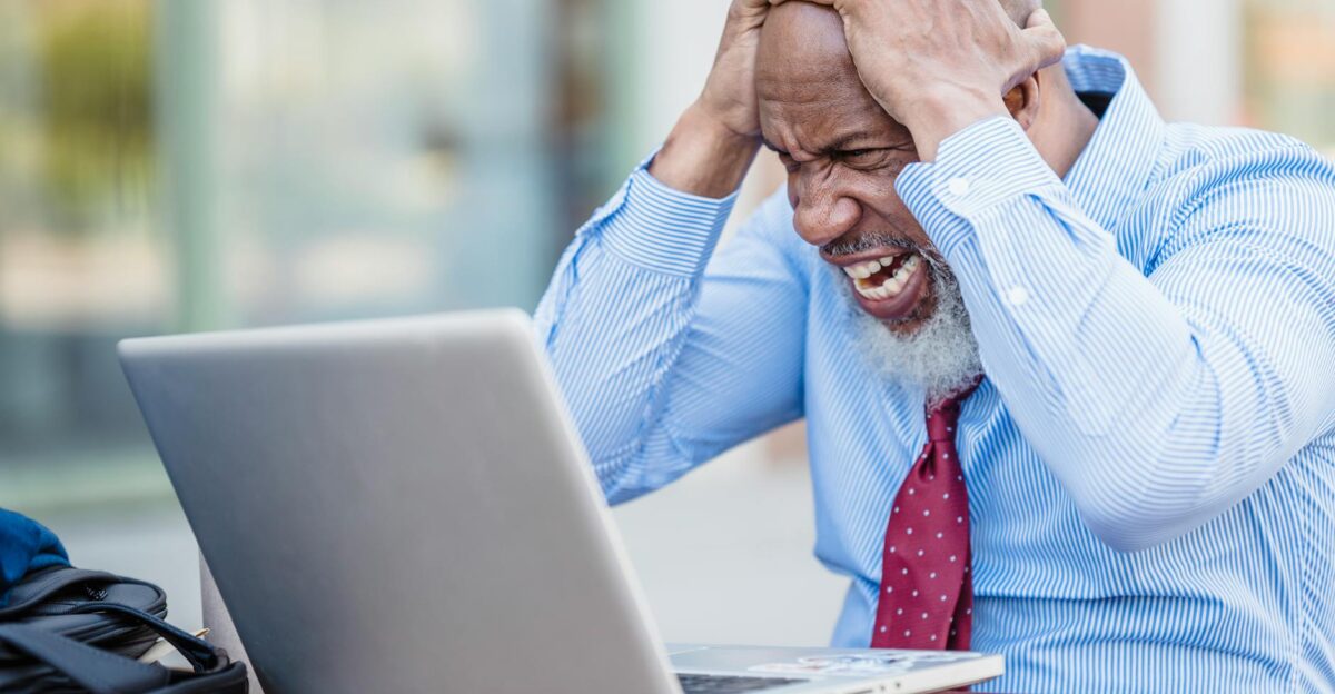 African American man showing frustration with laptop outdoors