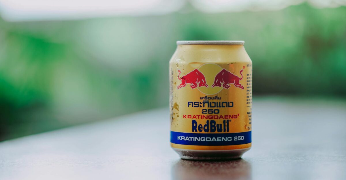 Close-up image of a Kratingdaeng energy drink can with condensation outdoors featuring vibrant colors