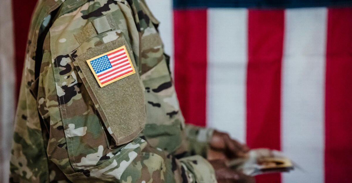 Close-up of a soldier in military uniform with American flag patch and background