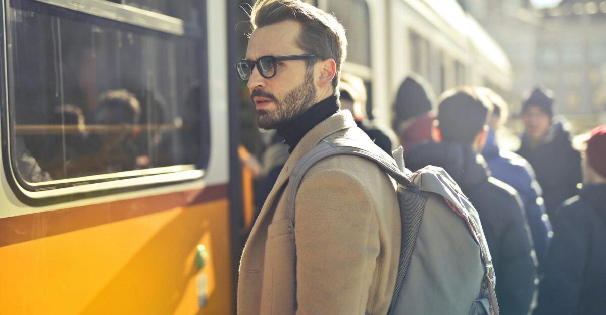A stylish man with a backpack boards a tram in bustling Budapest Hungary during the day