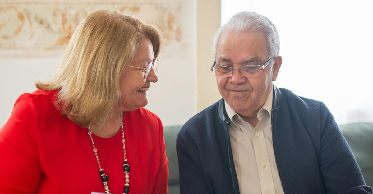 Senior couple consulting on pension options, smiling on a sofa, discussing documents.