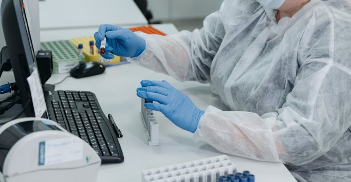 Professional female scientist in protective gear examining samples on a computer in a laboratory