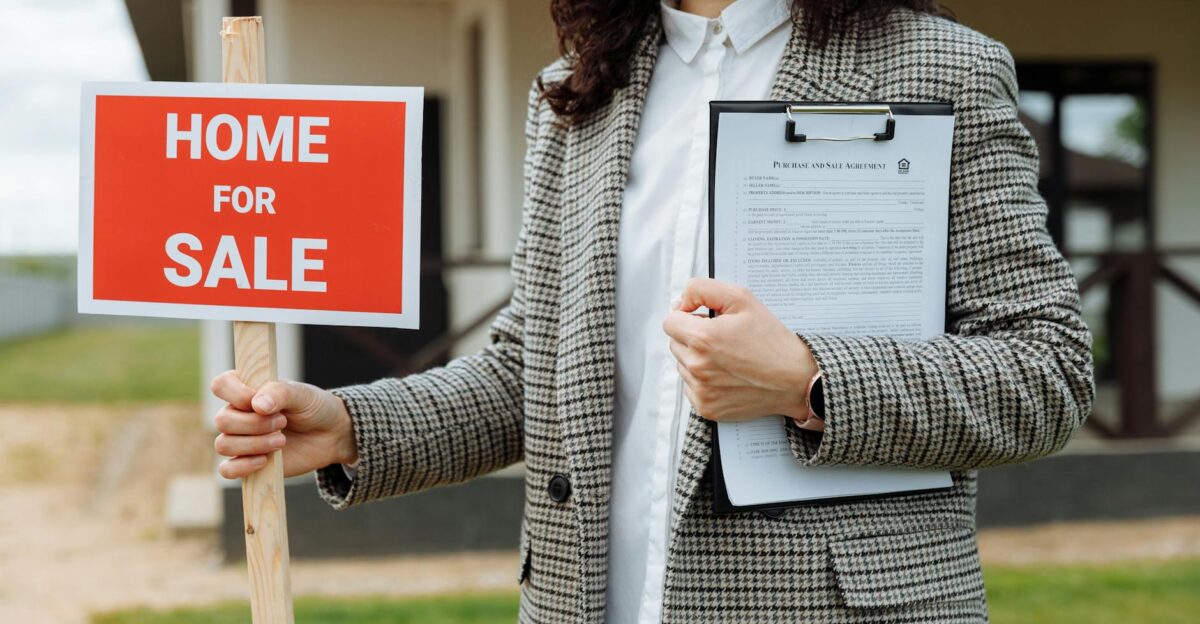 A real estate agent holding a home for sale sign and clipboard outside a property