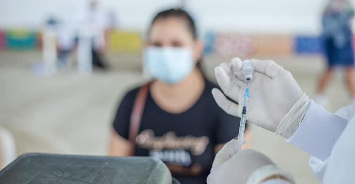 Healthcare worker prepares vaccine for patient in an indoor clinic setting