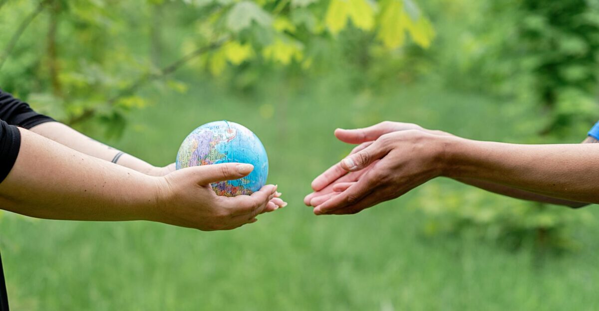 Two hands exchanging a small globe symbolizing global unity and ecology awareness