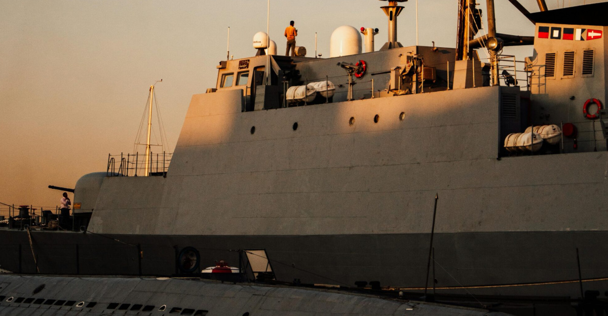 A naval ship and submarine docked at Saint Petersburg harbor during sunset.