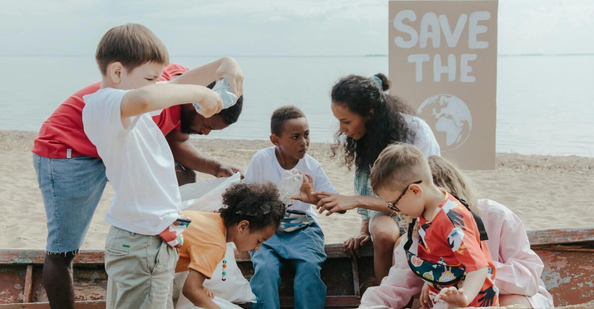 A group of children volunteering to clean a beach with a Save the Earth sign