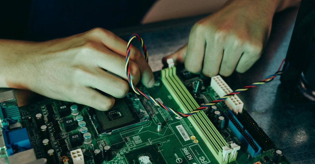 Person assembling computer motherboard with colorful wires showcasing technology and engineering