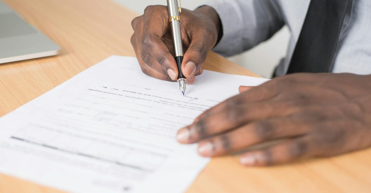 Close-up of a businessman signing a contract at an office desk