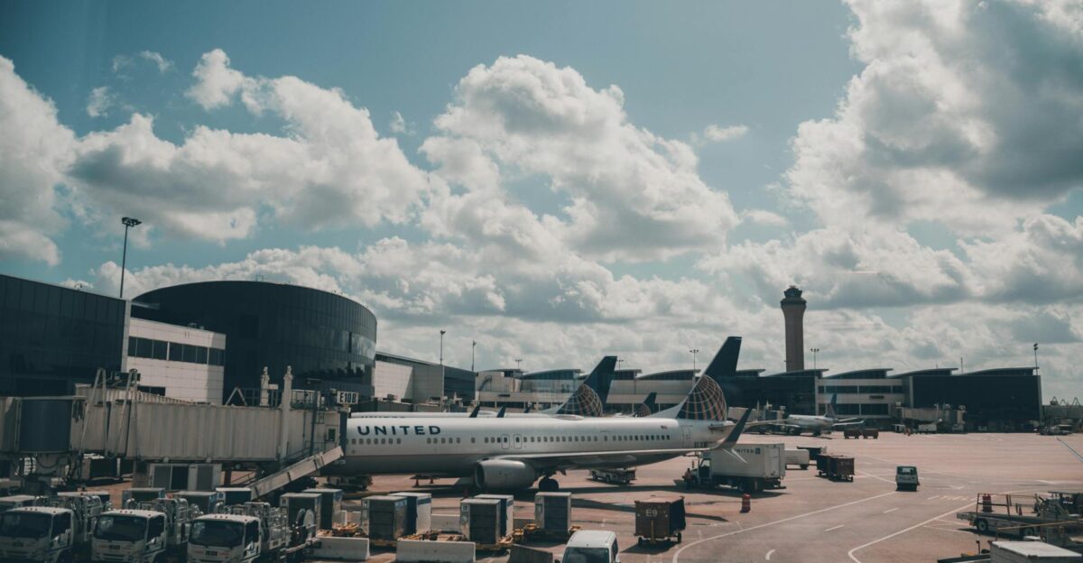 A United airplane parked on the airport apron under a scenic cloudy sky