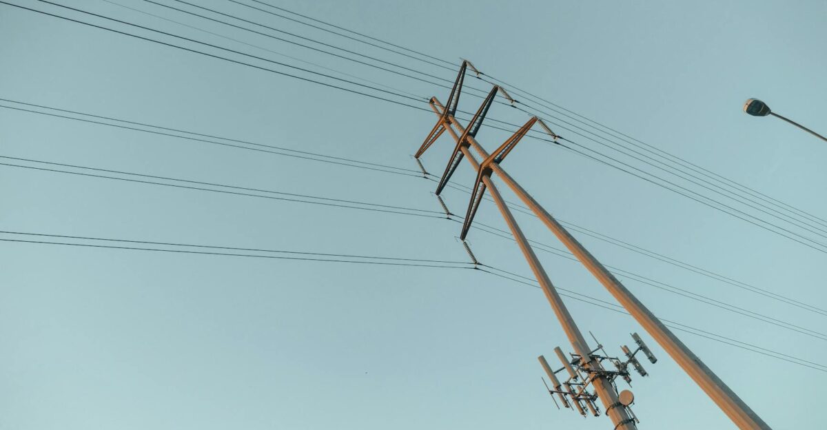 A captivating view of power lines stretching into the clear sky during sunrise symbolizing energy and connectivity