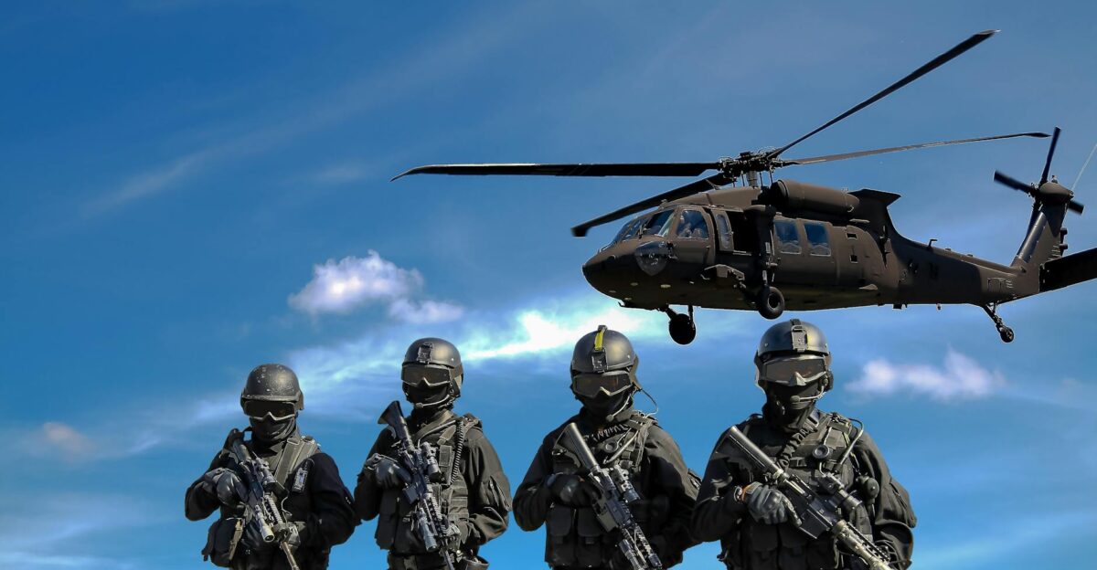 Special forces soldiers in tactical gear with helicopter overhead under a blue sky
