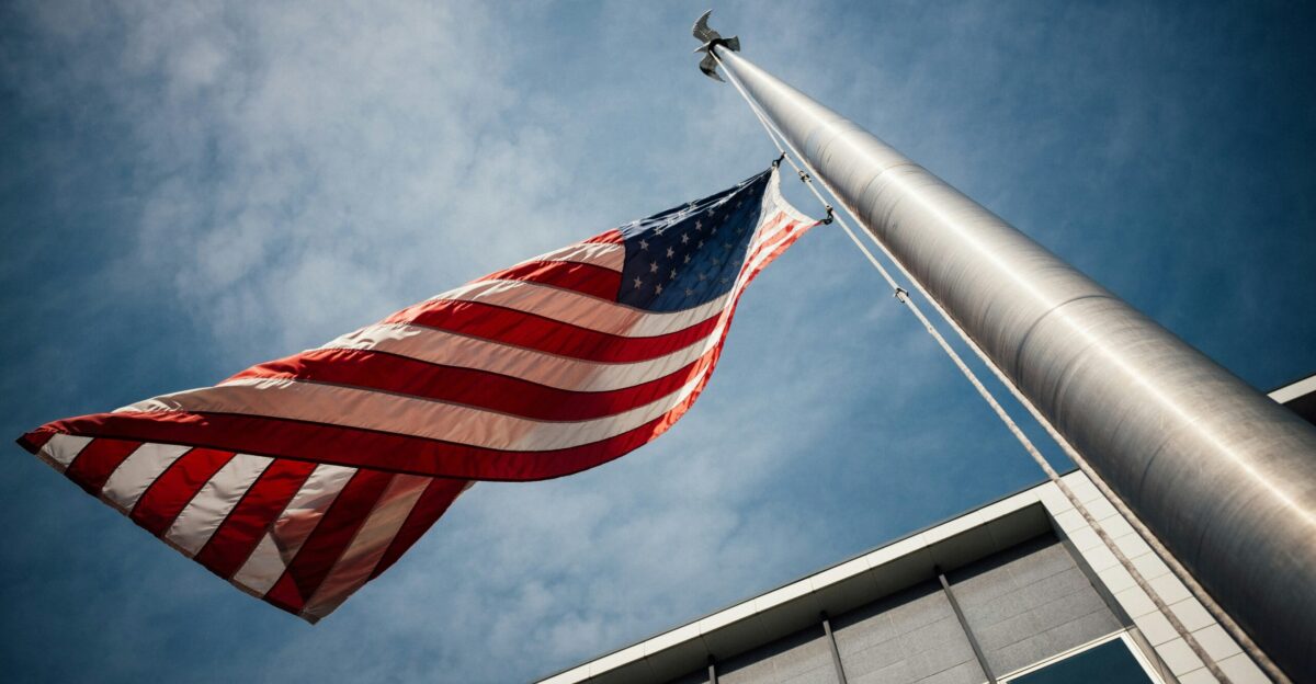 low-angle photo of U S flag placed on gray pole