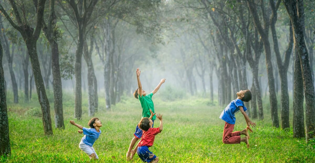four boy playing ball on green grass