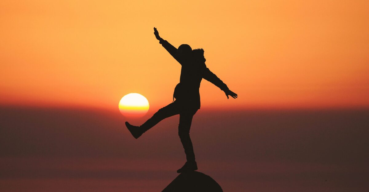 photo of silhouette photo of man standing on rock