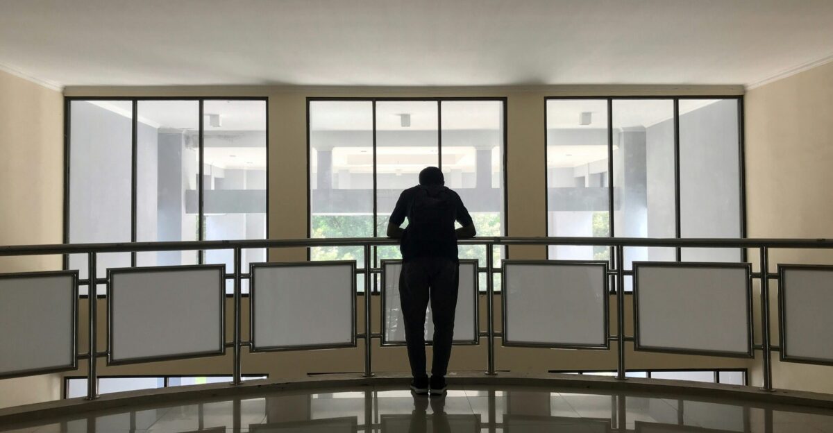 silhouette photography of person standing in front of railing