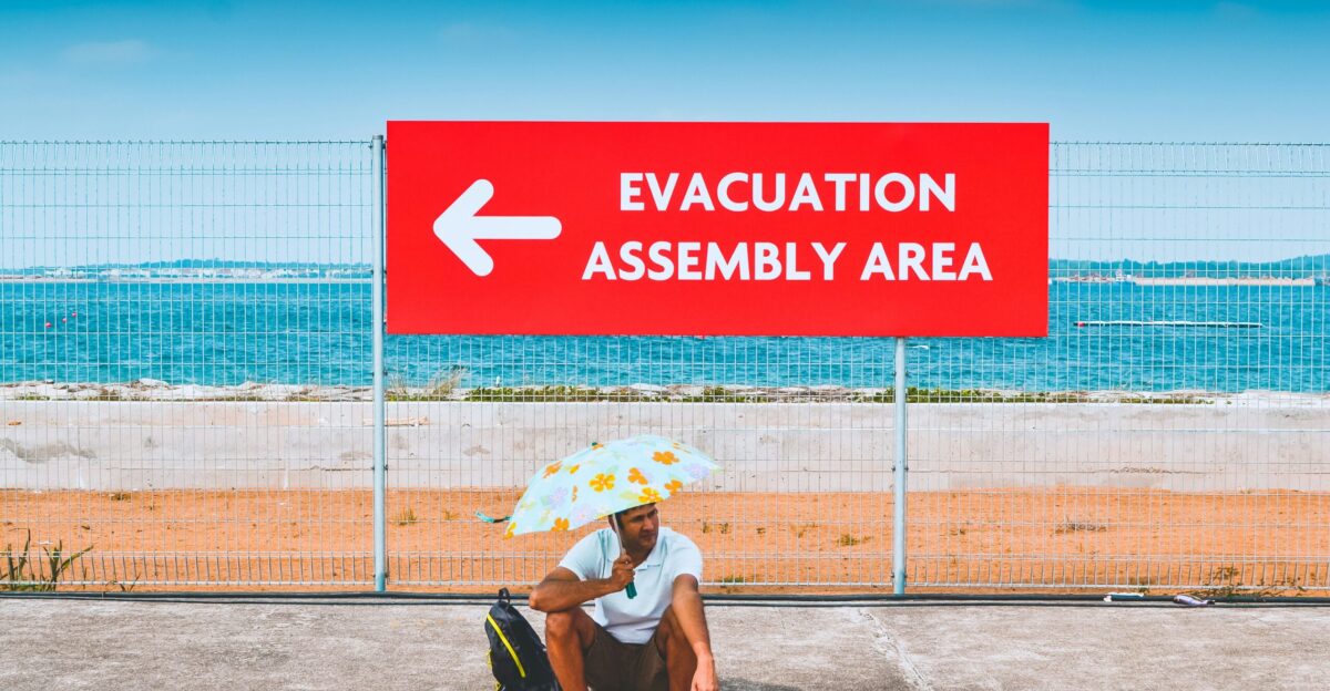 man sitting beside the road while holding an umbrella