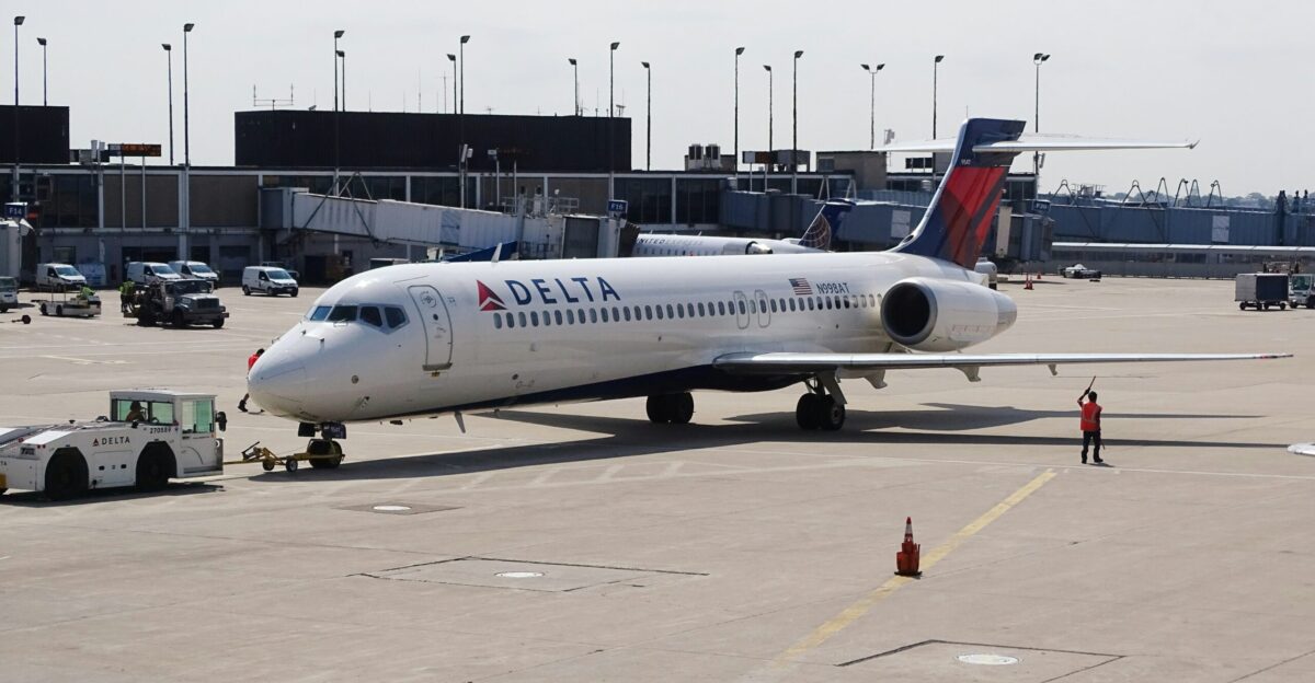 man standing beside white Delta airplane