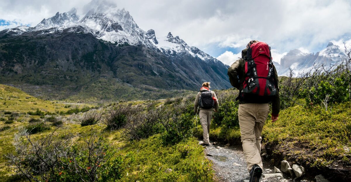 two person walking towards mountain covered with snow