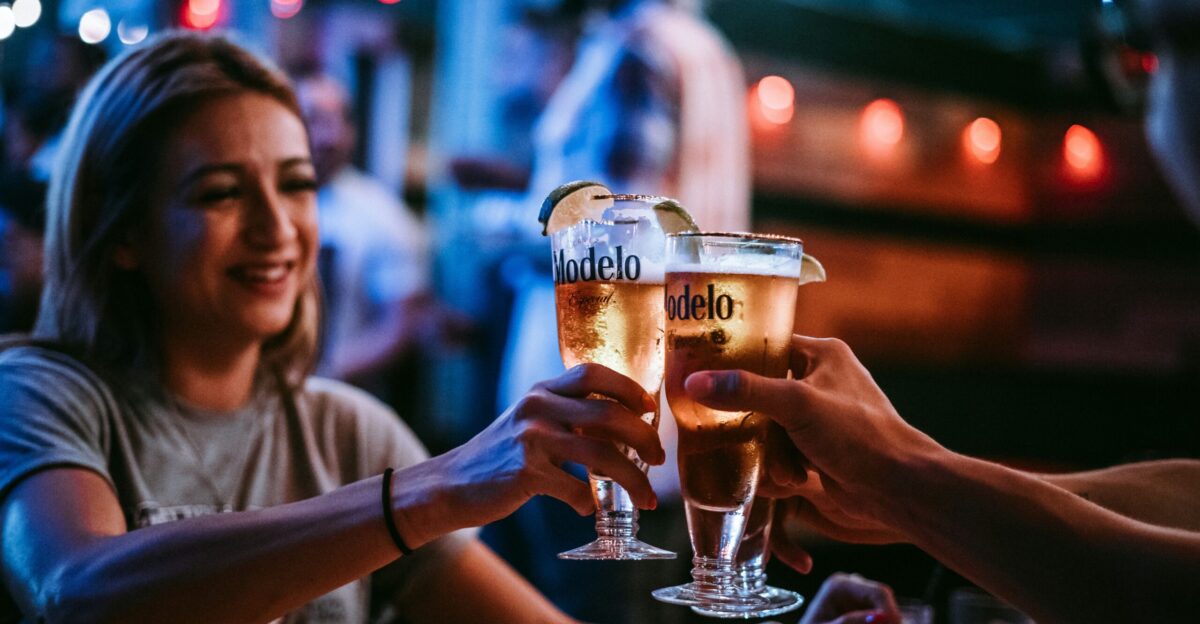 three persons toast their glasses at the bar