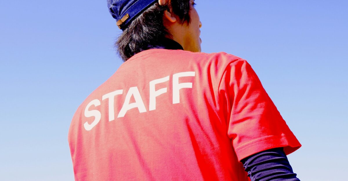 male staff wearing red t-shirt and blue hat standing