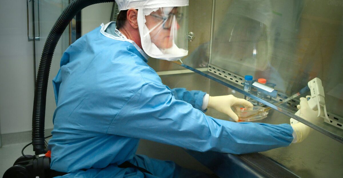 a man in a protective suit and mask working on a machine