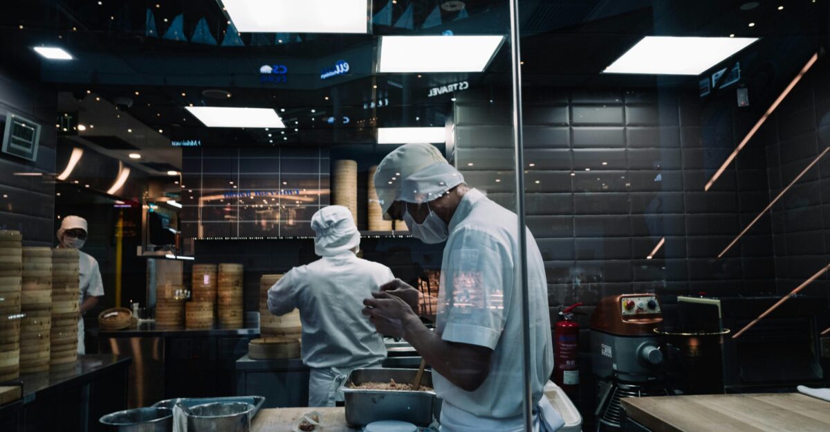 man in white long sleeve shirt and white pants standing in front of kitchen counter
