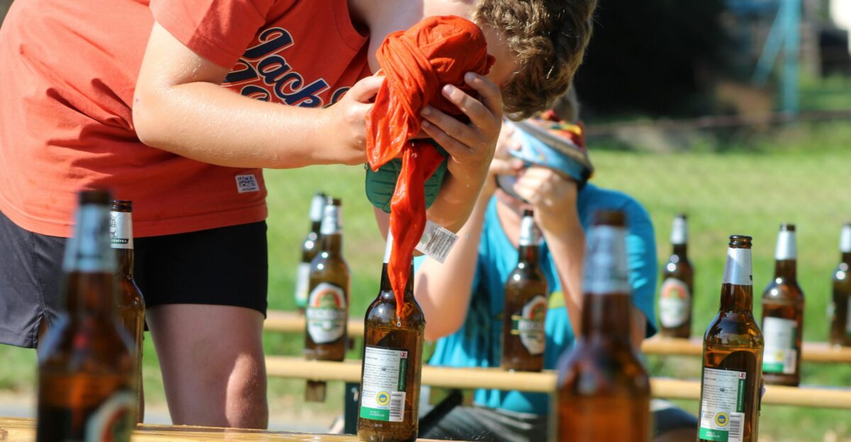 man in red crew neck t-shirt holding brown glass bottle