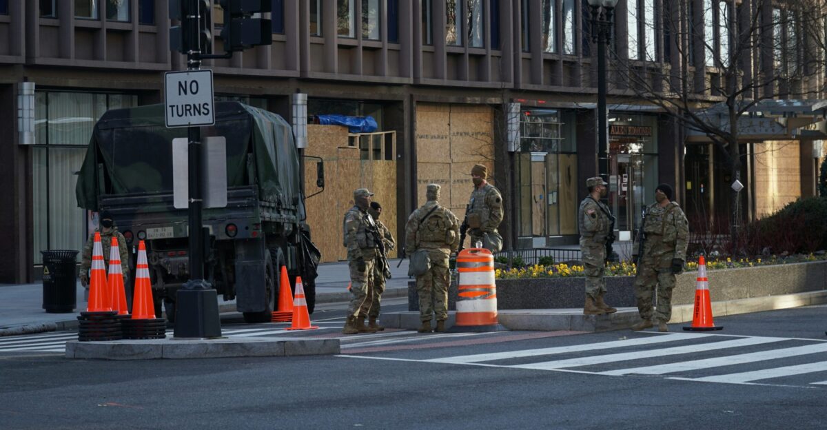 man in green and brown camouflage uniform standing on pedestrian lane during daytime